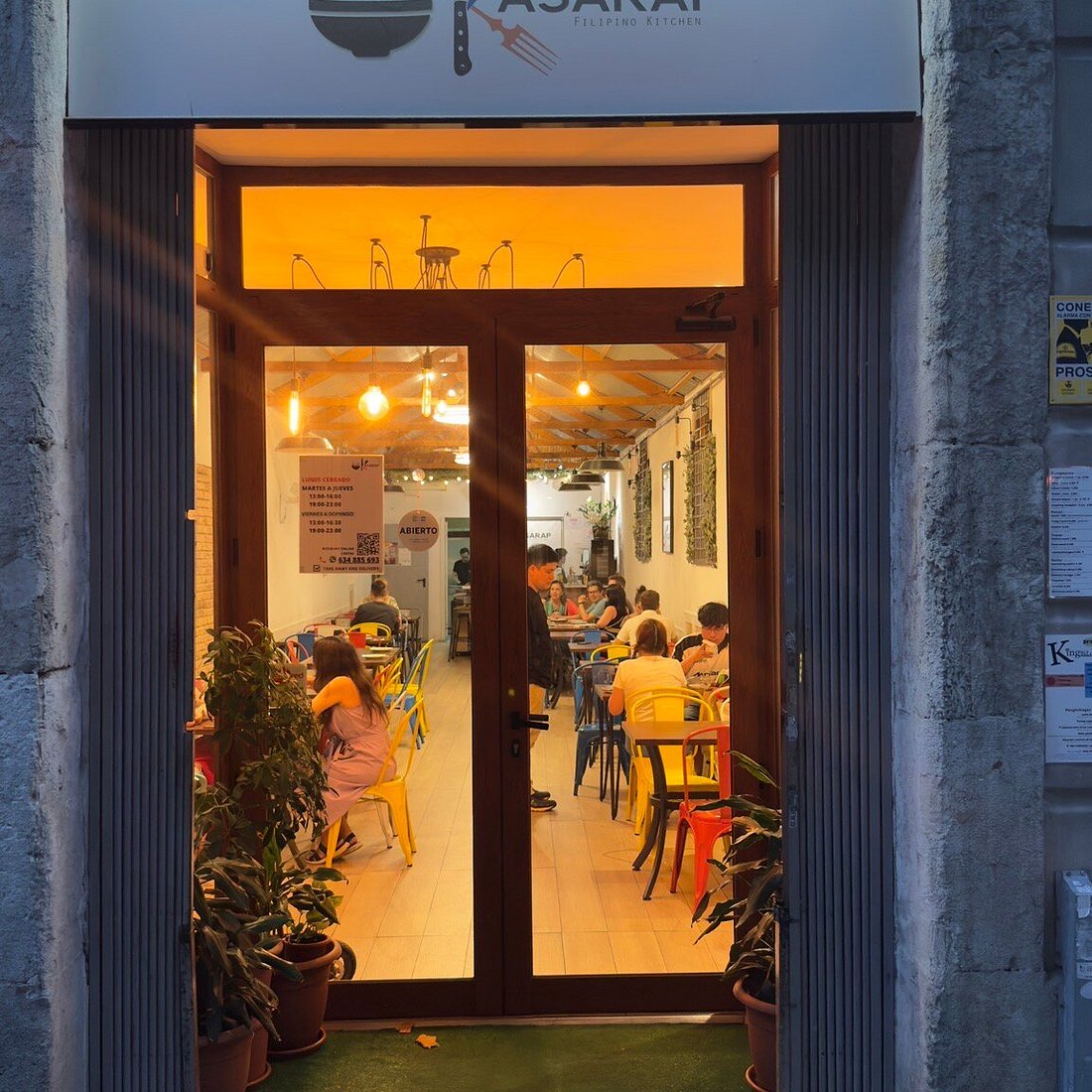 The illuminated wooden entrance and Kasarap sign on Carrer del Consell de Cent