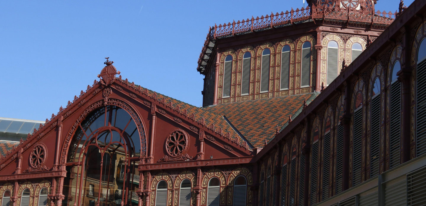 The ornate red iron entrance, tiled roof and central tower of Mercat de Sant Antoni